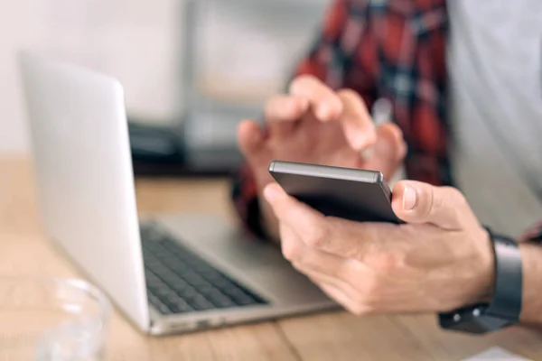 man using phone and computer while setting automated ad buying