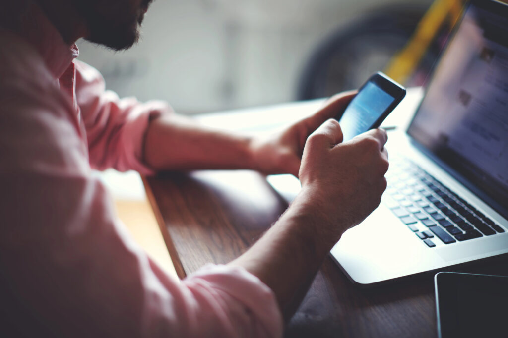 man using phone and computer while using programmatic advertising